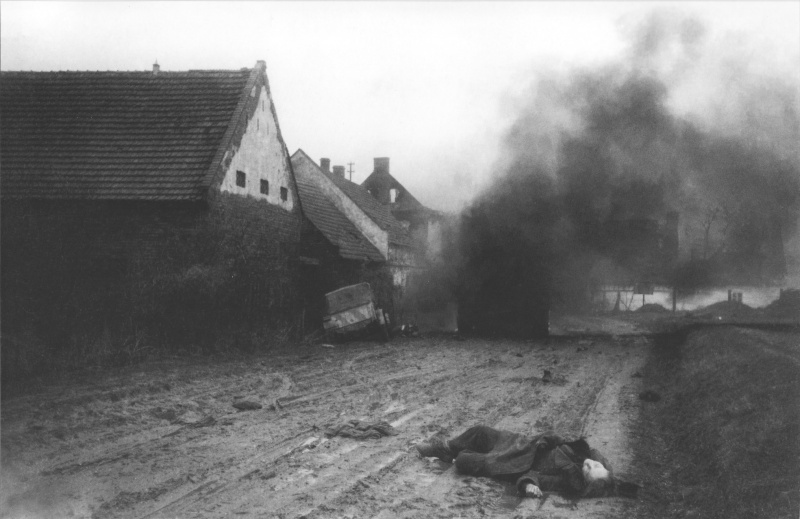 Немецкий автомобиль Кубельваген (Kubelwagen) попал под огонь на деревенской улице. Один пассажир автомобиля выскочил на ходу, но был застрелен на улице