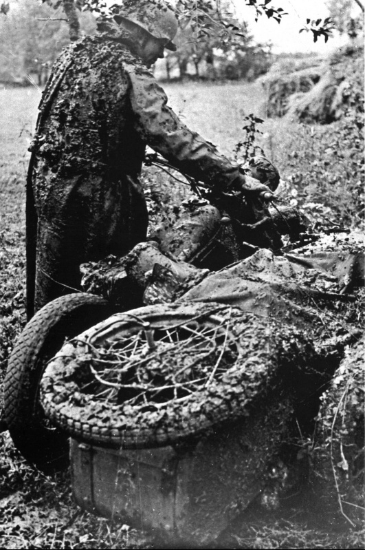 Немецкий мотоциклист вытаскивает из грязи свой застрявший мотоцикл Zundapp KS 750.