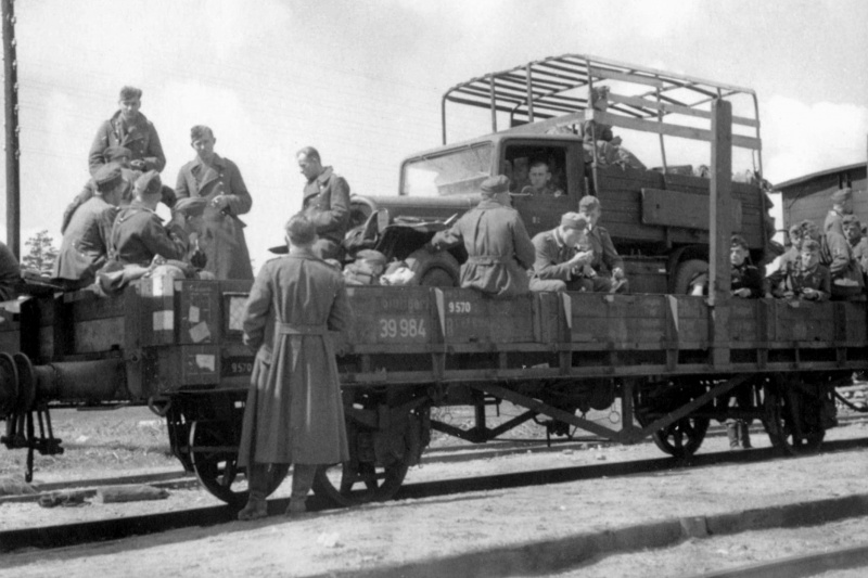 Немецкие солдаты на железнодорожной платформе с грузовым автомобилем.