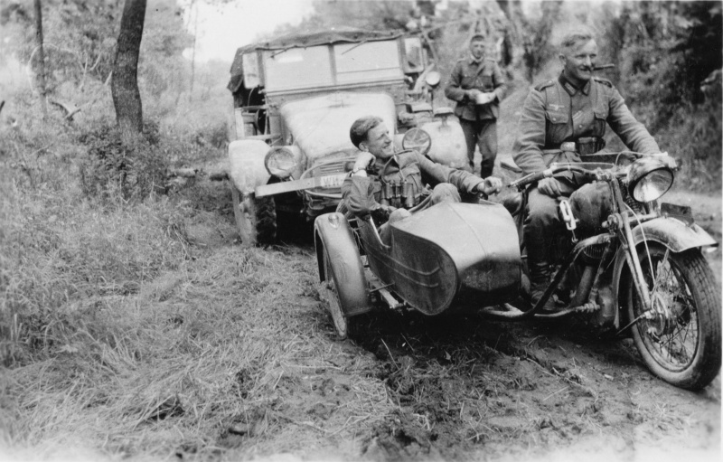 Немецкие солдаты на трофейном советском мотоцикле ТИЗ АМ-600 на лесной дороге. На втором плане — немецкий грузовик Крупп Протце (Krupp Protze, L2H43143) в варианте Kfz.69
